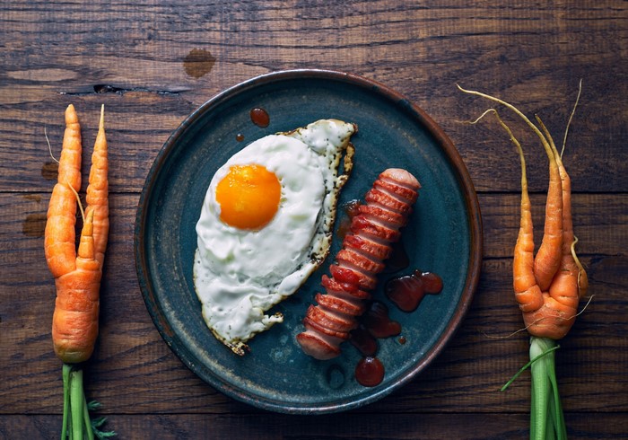Fried egg and sausage with carrots on a plate