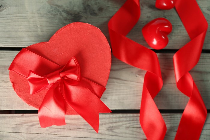Heart-shaped gift box with red ribbon and hearts