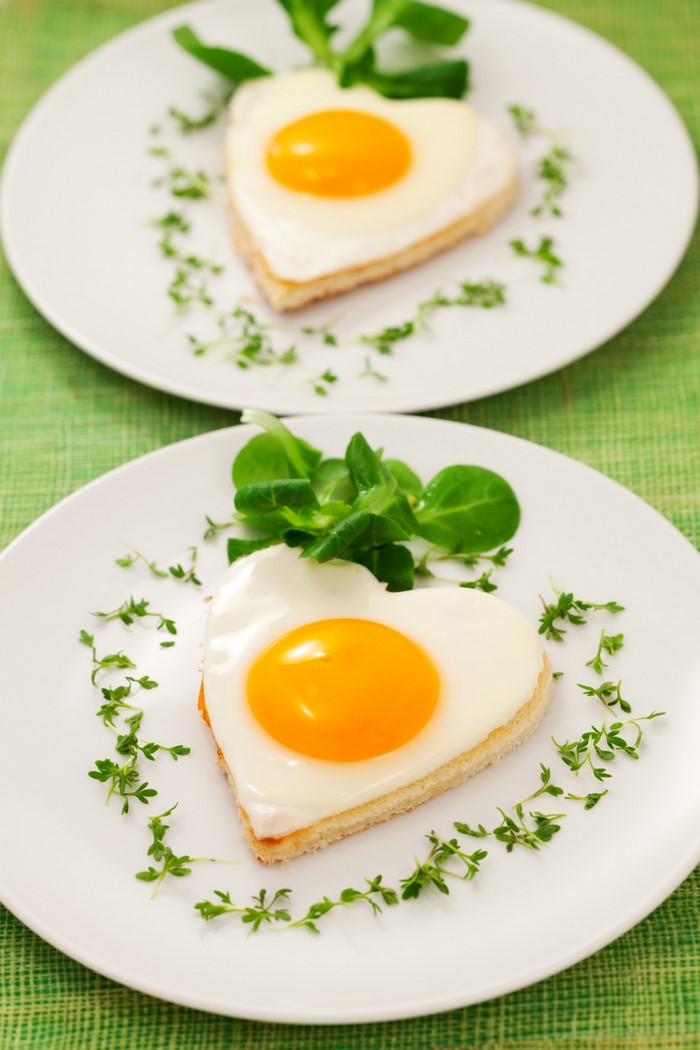 Two heart-shaped fried eggs on toast with garnish