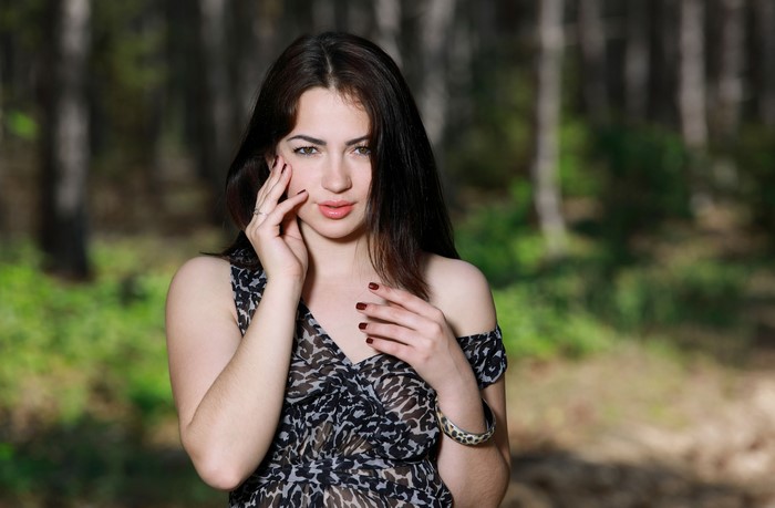 Brunette girl with hands near face in forest