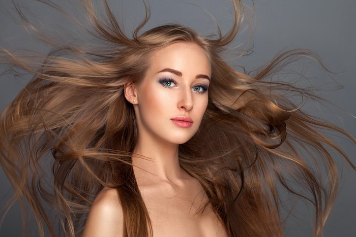 Woman with flowing brown hair on gray background