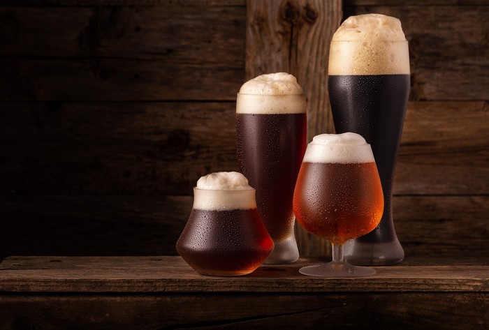 Four glasses of beer with foam on a wooden surface
