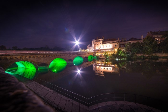 Bridge over river at night with green lights and reflections