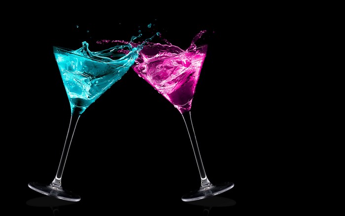 Two cocktails splashing against black background
