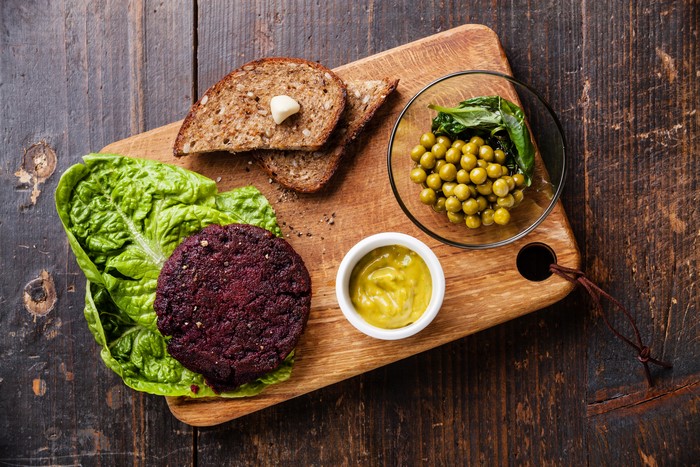 Beetroot burger with peas and bread on a cutting board