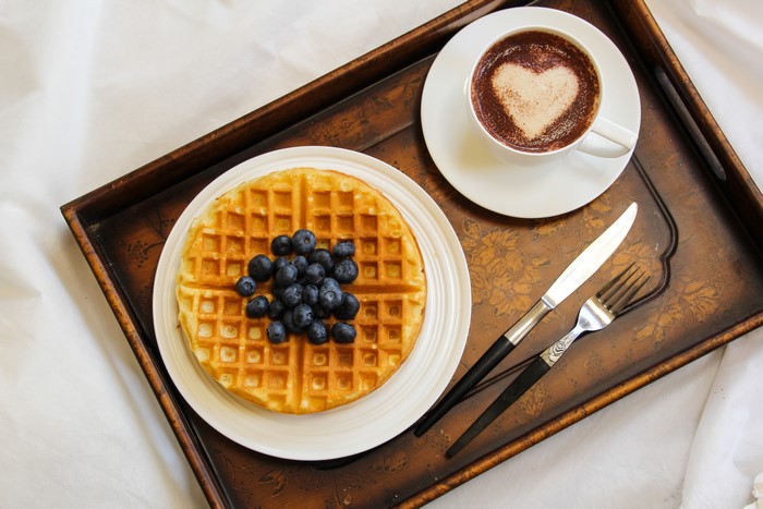 Waffles with blueberries and cappuccino on a tray