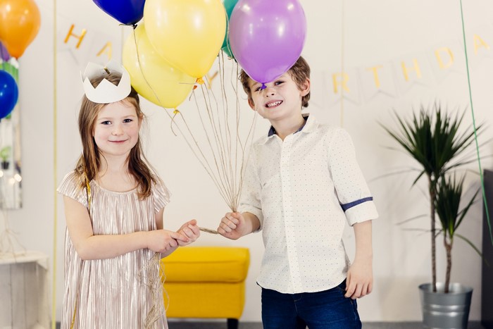 Two children holding balloons at a birthday party