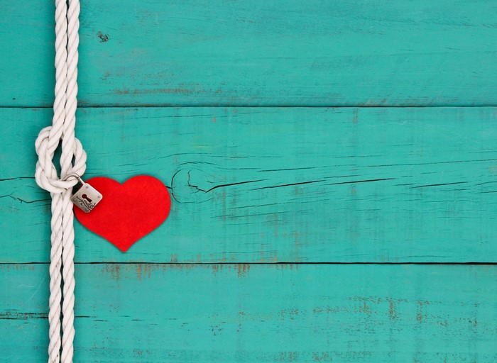 Red heart locked with a rope on a wooden background