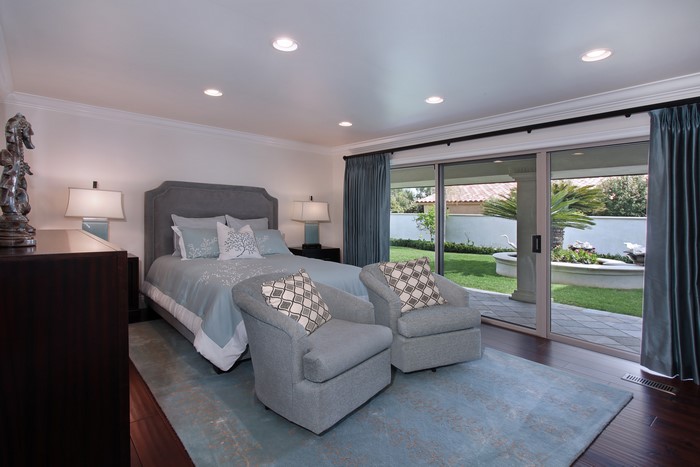 Bedroom with bed, armchairs, and sliding glass door to yard
