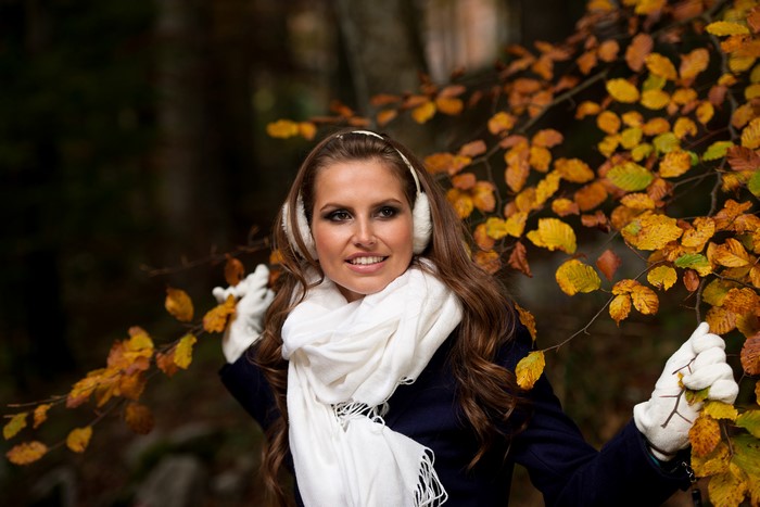Woman with headphones and scarf in autumn forest