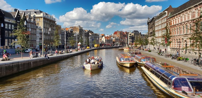 Amsterdam canal with riverboats and buildings
