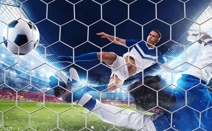 Soccer players in action through a net