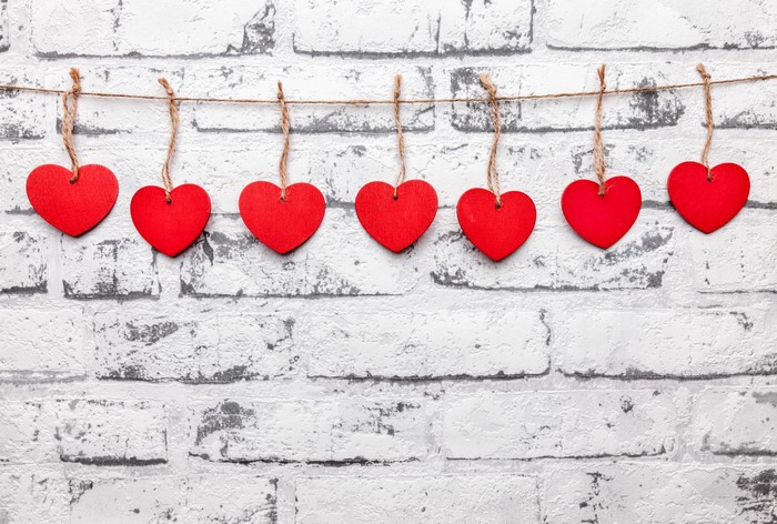 Red hearts hanging on a string against a brick wall