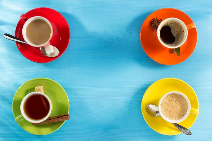 Four cups of coffee and tea on colorful saucers