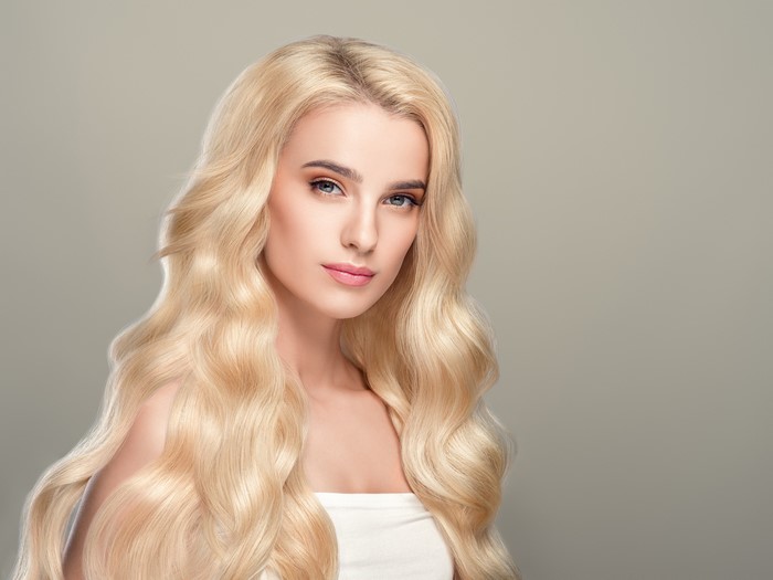 Blonde woman with wavy hair on gray background