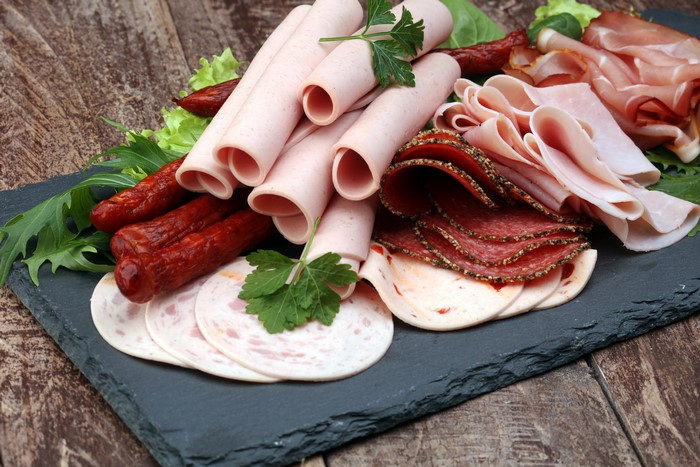 Meat products, sausage, ham, and sliced food on a slate board