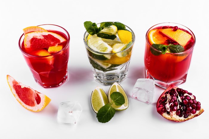 Cocktails with grapefruit, lime, and pomegranate on white background