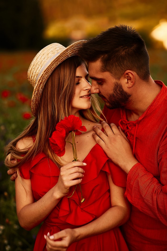 Couple in a poppy field holding a red flower