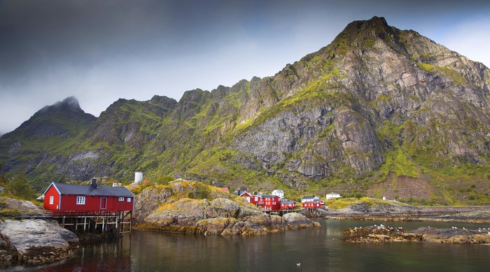 Red houses on stilts in Lofoten, Norway with mountains
