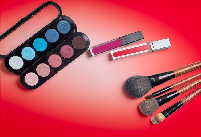 Makeup products and brushes on red background