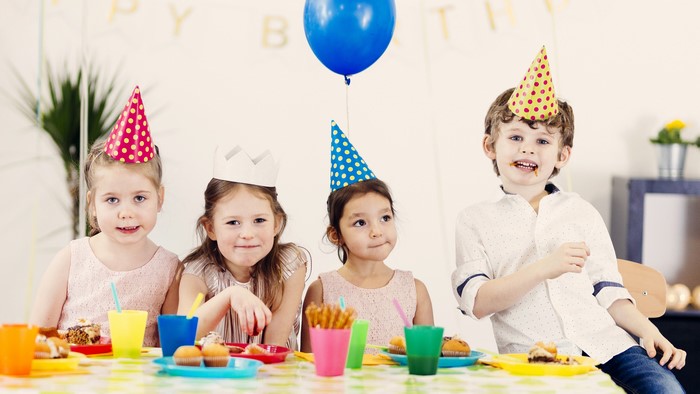 Children at a birthday party with party hats and cake