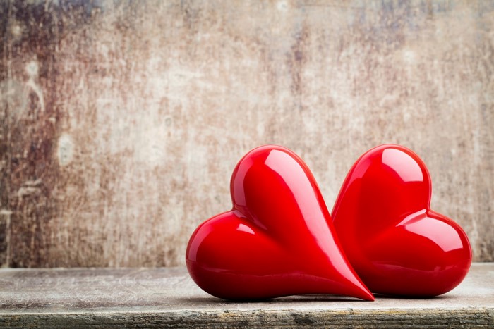Two red hearts on a wooden surface