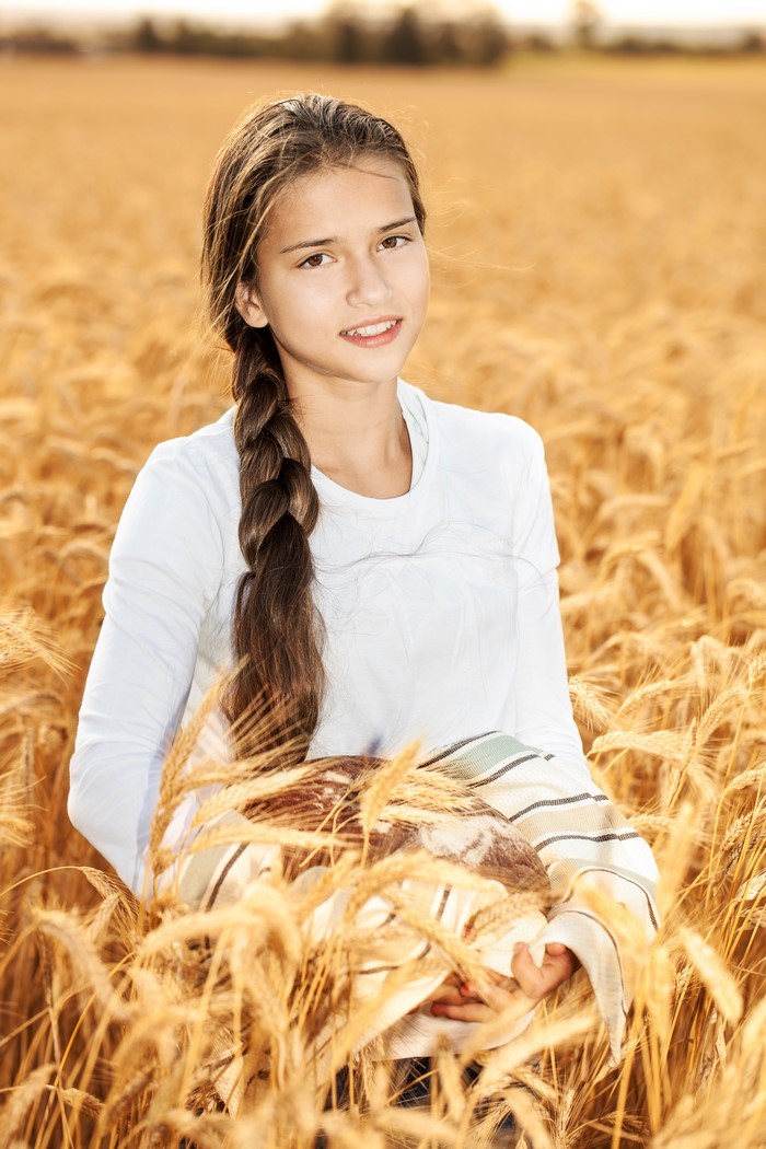 Girl in a wheat field holding bread