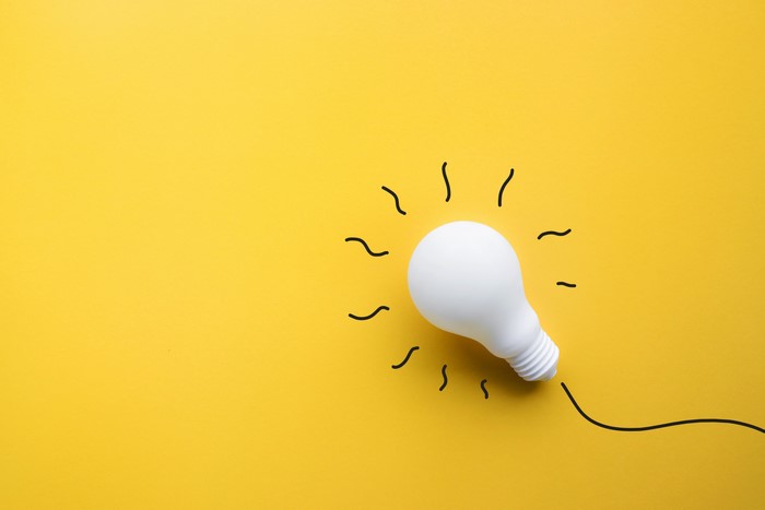 White light bulb with drawn rays on yellow background