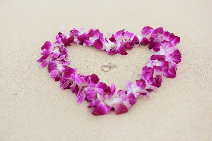 Wedding rings on a beach with flower lei
