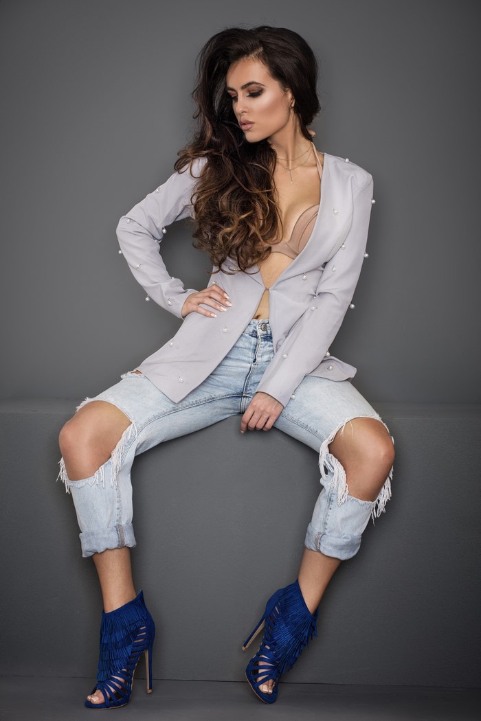 Woman in ripped jeans and blazer sitting