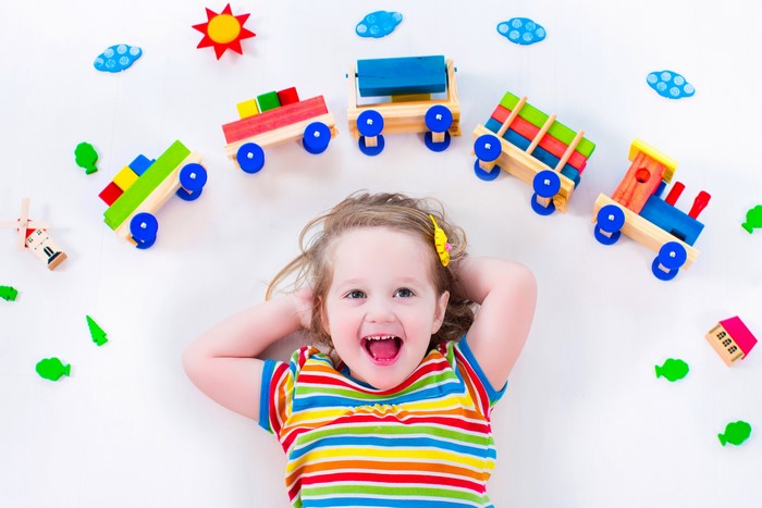 Little girl with toy train on white background