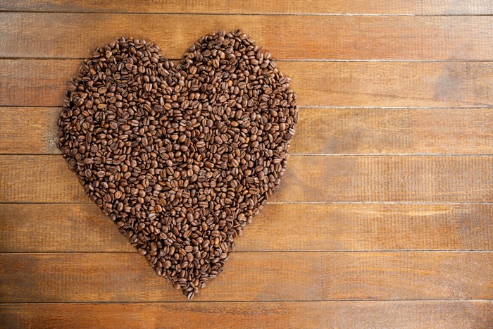 Heart shape made of coffee beans on wood planks