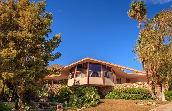 Mid-century modern house with stone base and palm trees