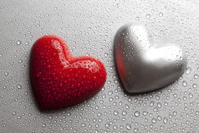 Two hearts with water drops on a gray background