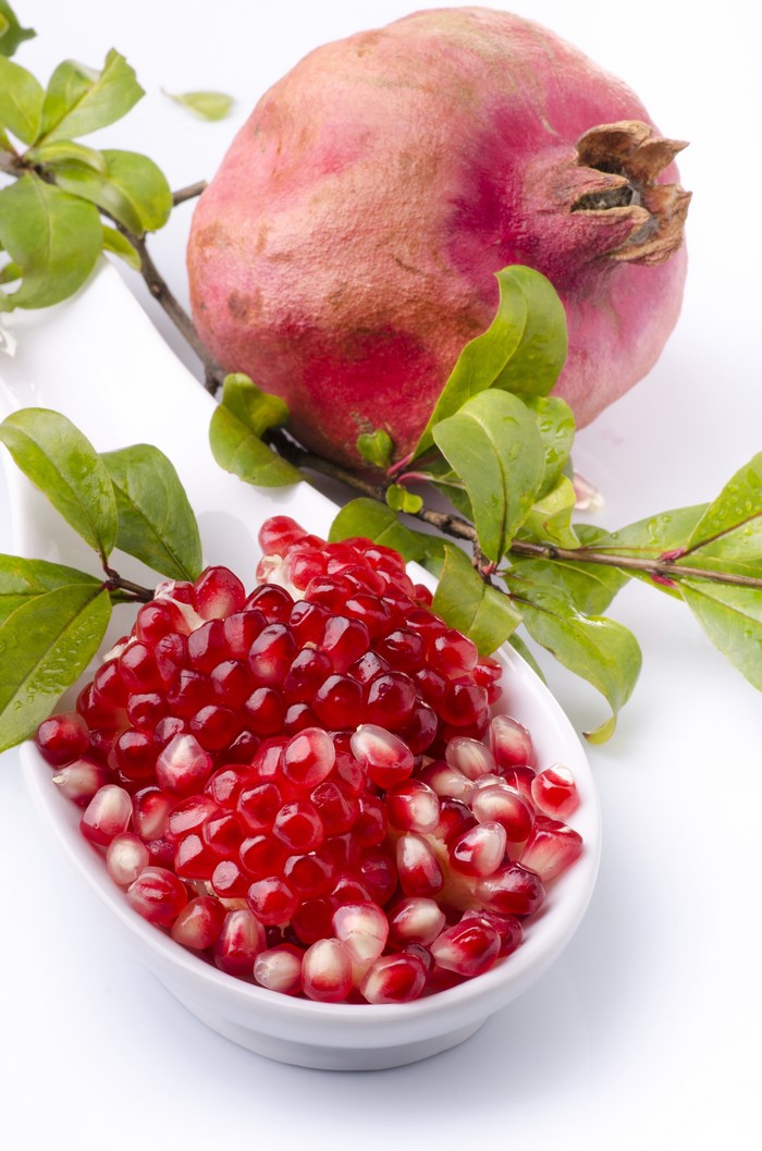 Pomegranate seeds and whole fruit with leaves
