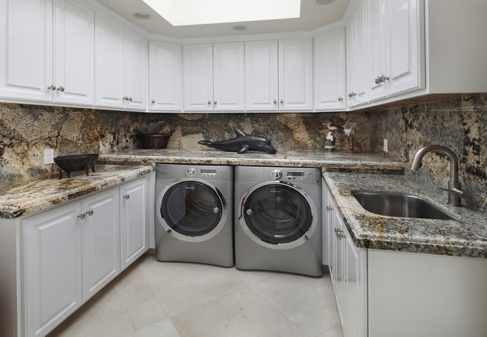 Laundry room with white cabinets and granite countertops