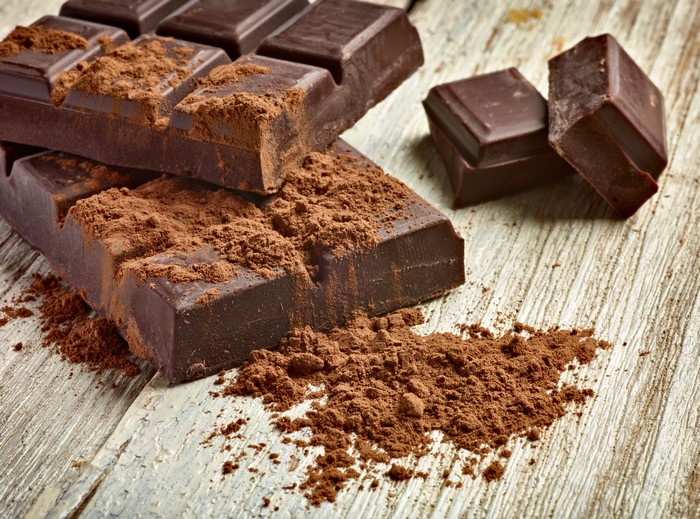 Chocolate bar with cocoa powder on wood planks