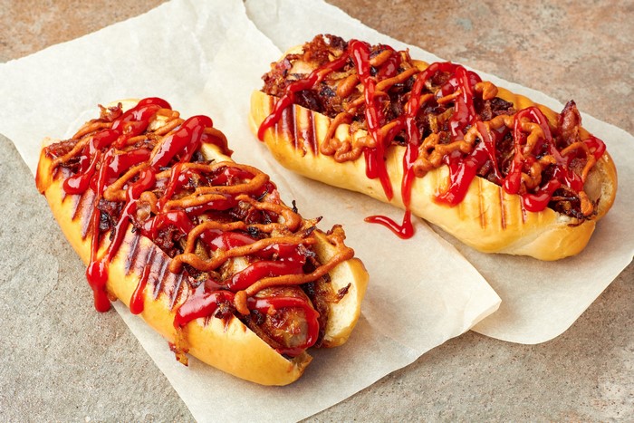 Two hot dogs with ketchup and fried onions
