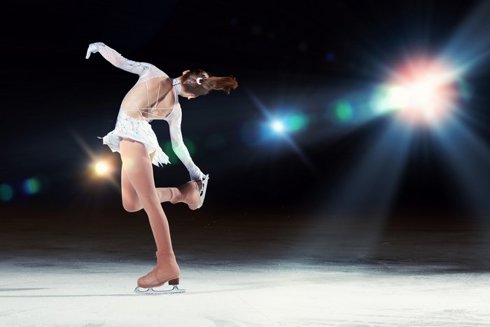 Figure skater performing on ice with spotlights