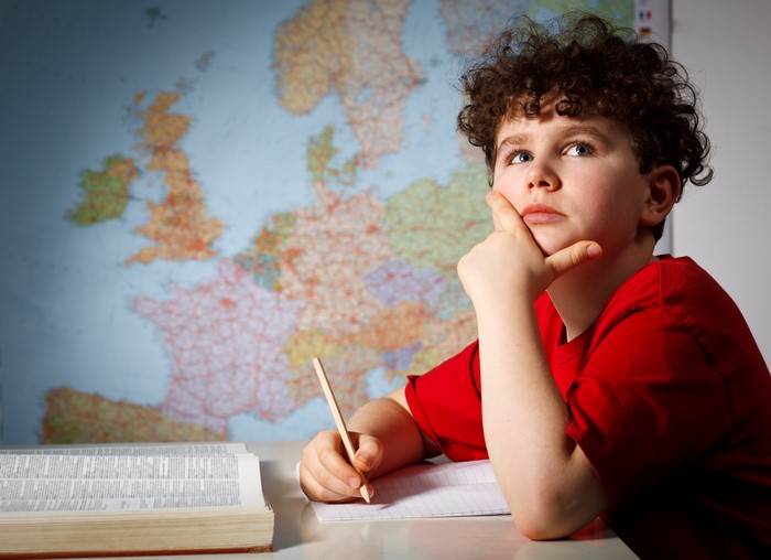 Boy with curly hair thinking in front of a map