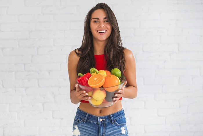 Woman holding a bowl of fruits and vegetables