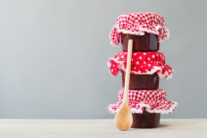 Three jars of jam with a wooden spoon