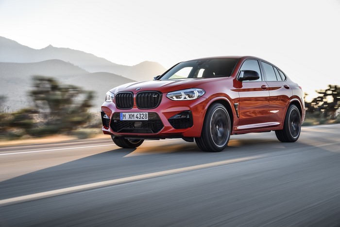 Red BMW Competition X4M F98 driving on a road