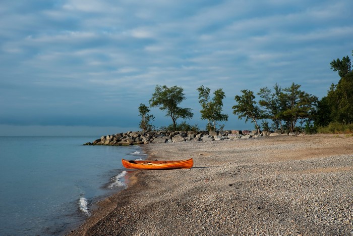 Orange canoe on a pebble beach by Lake Ontario
