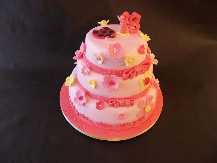 Pink three-tier birthday cake with ladybug and '18' topper