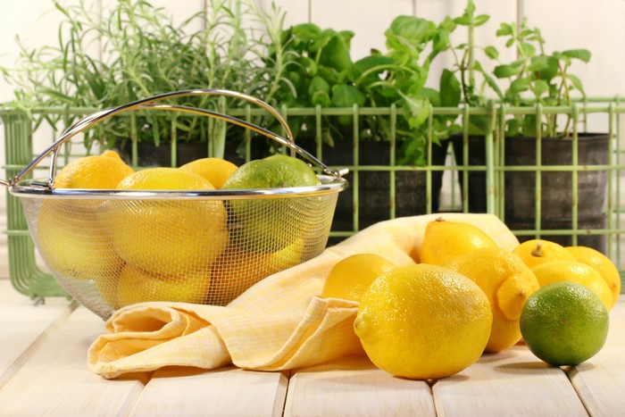 Lemons and limes in a basket with herbs