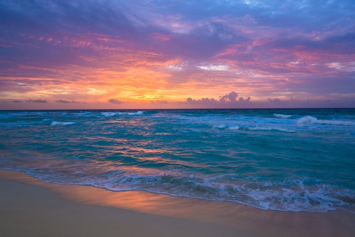 Sunset over the ocean with waves and beach