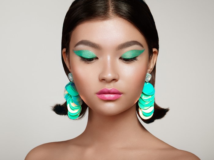 Asian woman with green eyeshadow and earrings