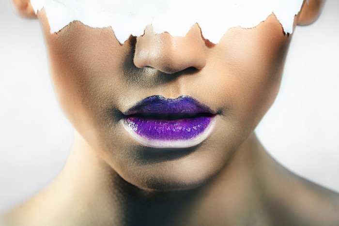 Close-up of woman's face with purple lipstick and white paint