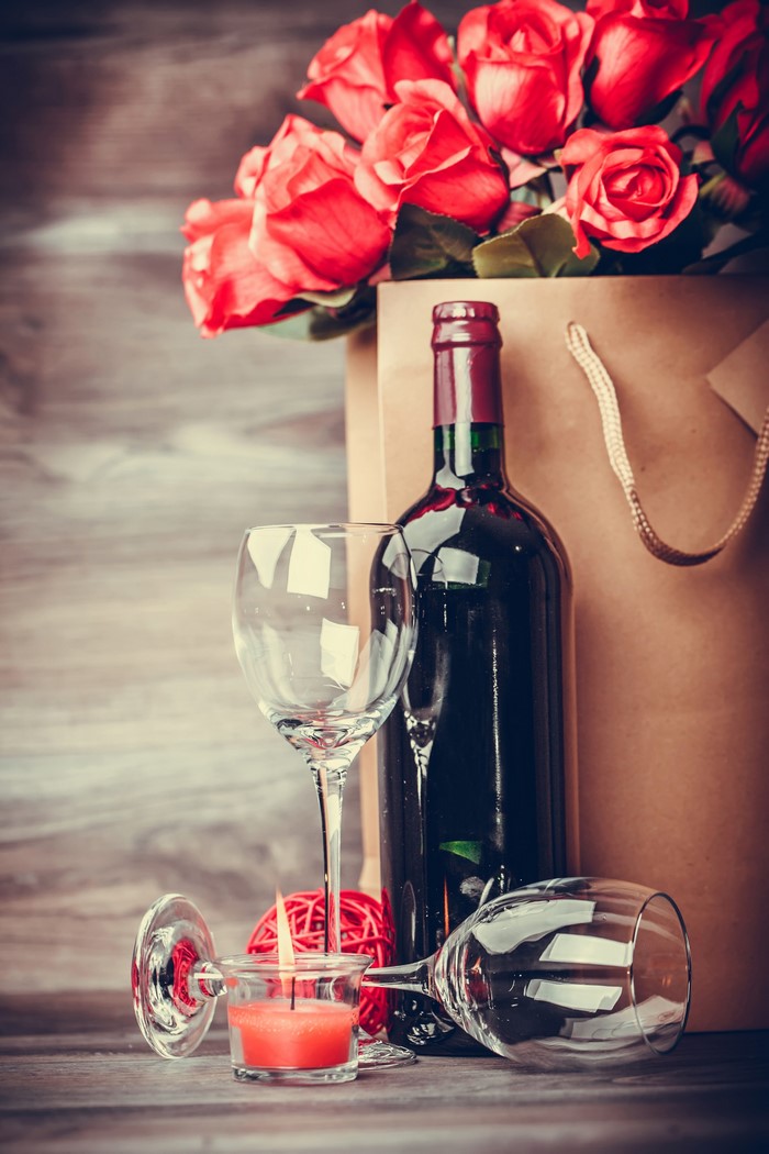 Red roses, wine bottle, glasses, and candle